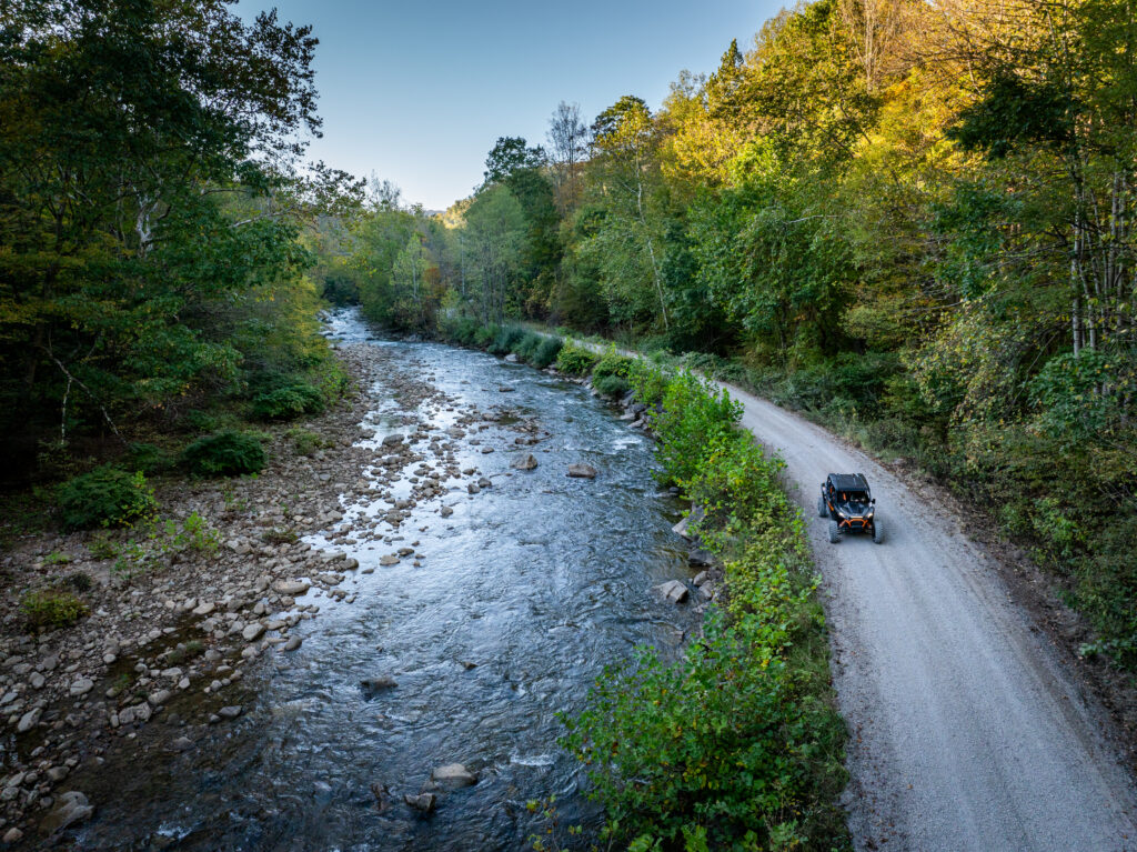 Side by side rides on country road in woods next to river in Richwood, West Virginia