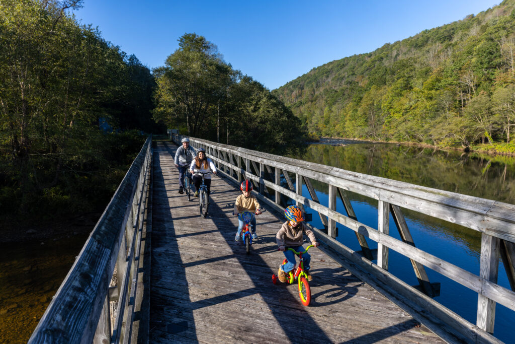 Family rides across wooden railroad trestle on Cranberry Tri-Rivers Trail in Richwood