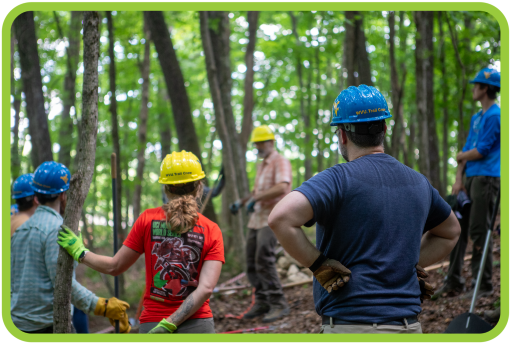 Partnership Members and Community Volunteers stand in forest during trail stewardship course.