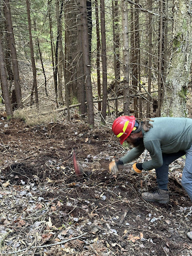 AmeriCorps in PPE swings tool to build new trail during US Forest Service stewardship training.